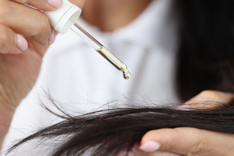 Castor oil being added to hair with dropper